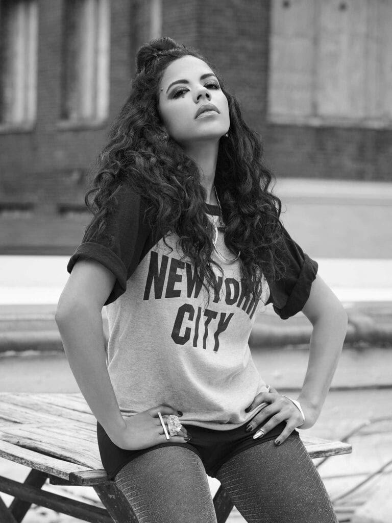 A black-and-white portrait of Roxiny wearing a t-shirt that reads "New York City"